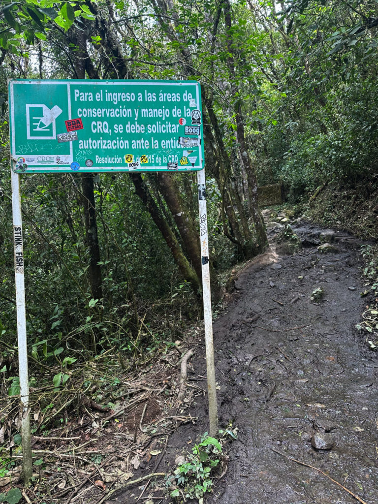 Main trail continues left up and incline and past this green sign